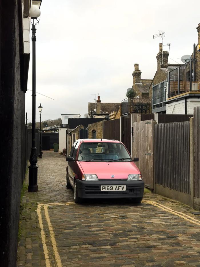 Pink Fiat Cinquecento in a cobbled lane